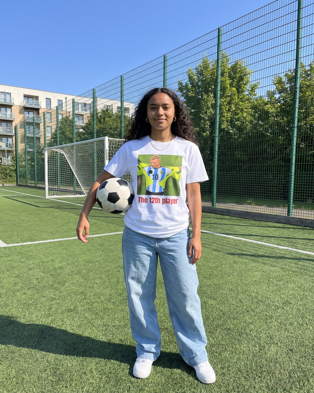 Fan on a football pitch holding a ball, wearing the Le 12ème joueur tee