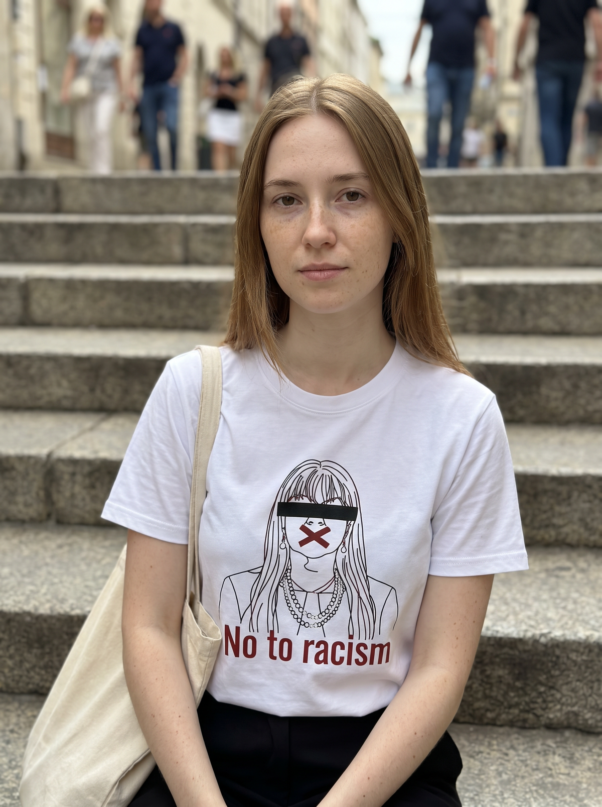 Calm portrait on stone city steps wearing the No to Racism tee